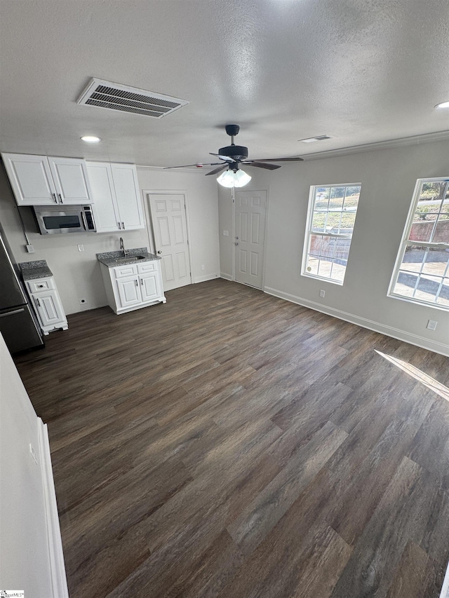 kitchen featuring visible vents, white cabinets, stainless steel microwave, dark wood-style flooring, and a textured ceiling