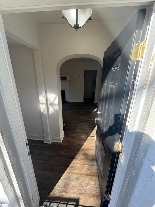 hall with arched walkways and dark wood-style flooring