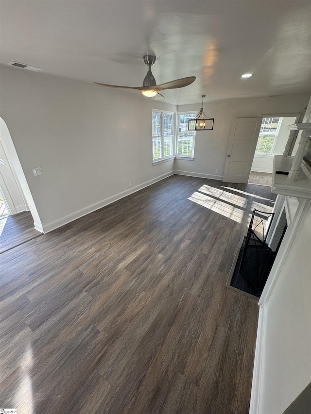 unfurnished living room featuring dark wood-style floors, baseboards, and a ceiling fan