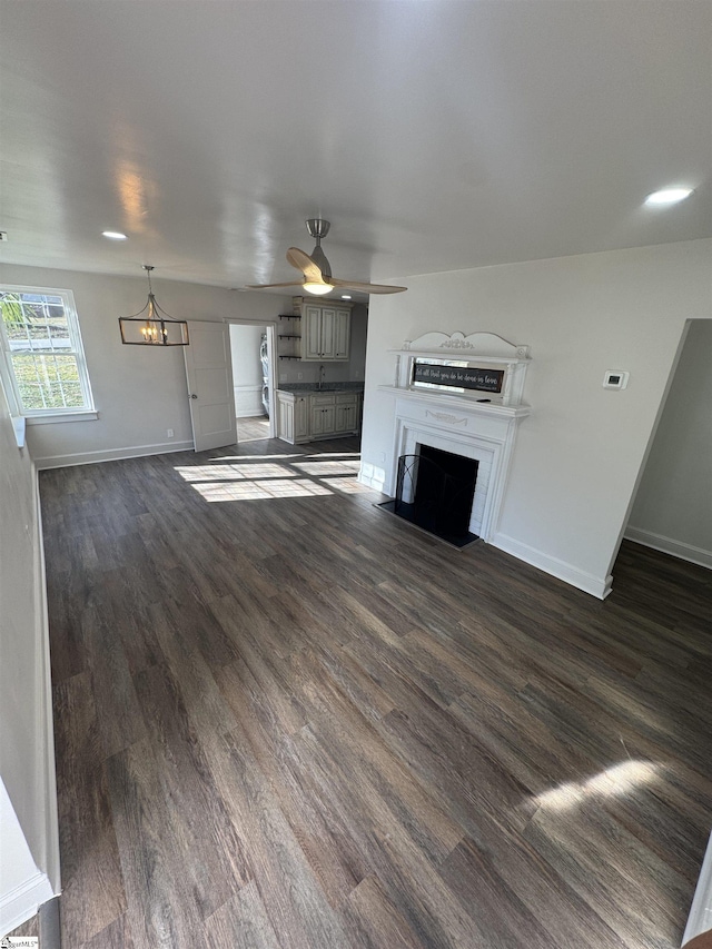 unfurnished living room featuring dark wood-style floors, a fireplace with flush hearth, baseboards, and a ceiling fan