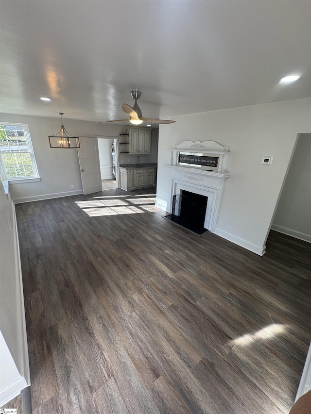 unfurnished living room featuring a fireplace with flush hearth, baseboards, ceiling fan, and dark wood-style flooring