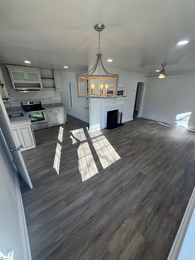 interior space featuring recessed lighting, ceiling fan with notable chandelier, a sink, baseboards, and dark wood finished floors