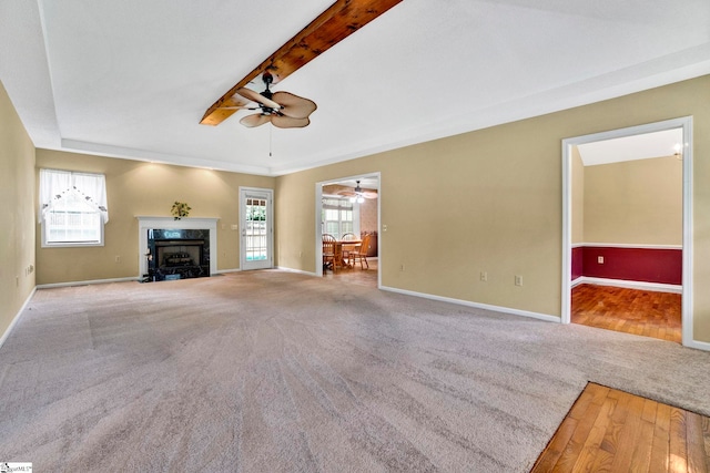 unfurnished living room featuring baseboards, a premium fireplace, carpet flooring, and a healthy amount of sunlight