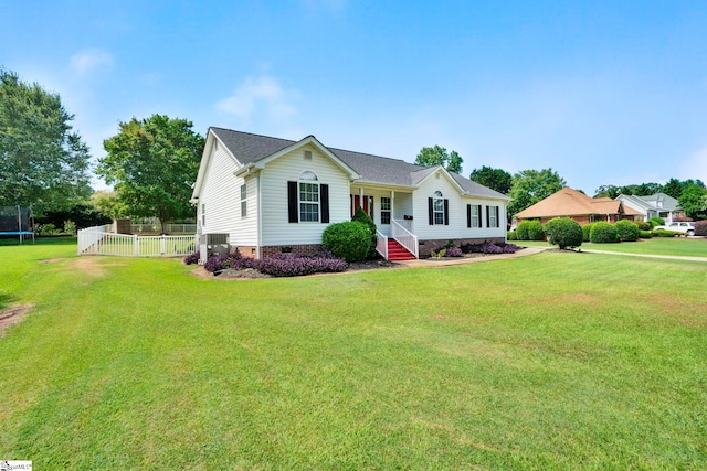 single story home featuring a trampoline, fence, and a front lawn