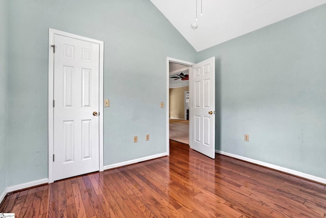 unfurnished bedroom featuring high vaulted ceiling, wood finished floors, and baseboards