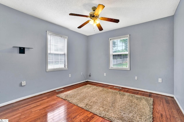 empty room featuring visible vents, baseboards, wood-type flooring, ceiling fan, and a textured ceiling