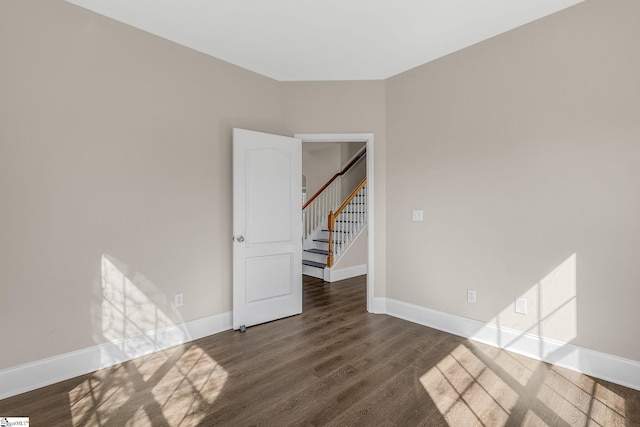 spare room featuring stairs, baseboards, and wood finished floors