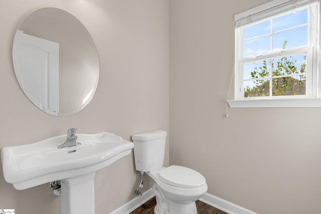 half bathroom featuring baseboards, toilet, and wood finished floors