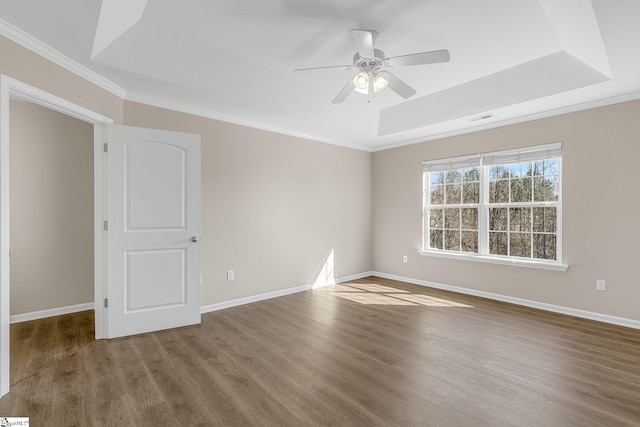 unfurnished room featuring a tray ceiling, visible vents, baseboards, and wood finished floors