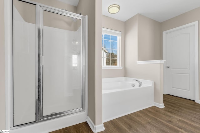 full bath with a stall shower, a garden tub, and wood finished floors