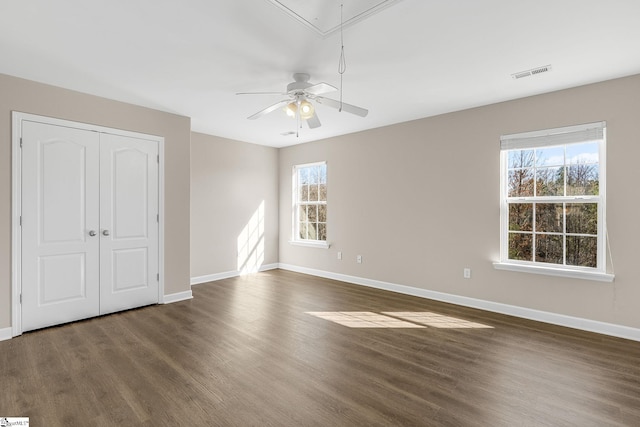 spare room featuring attic access, a healthy amount of sunlight, visible vents, and wood finished floors