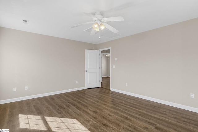 empty room with dark wood-style floors, visible vents, ceiling fan, and baseboards