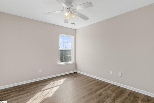 spare room featuring ceiling fan, wood finished floors, visible vents, and baseboards