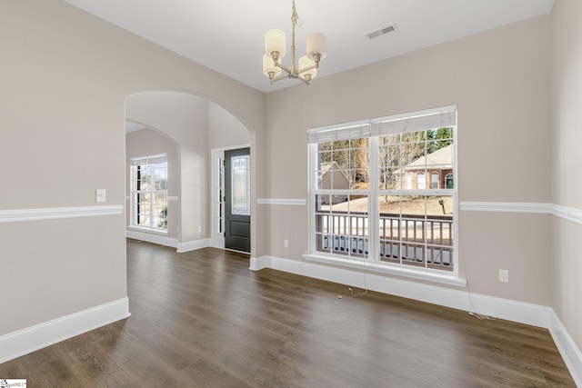 unfurnished dining area featuring baseboards, visible vents, a chandelier, and wood finished floors