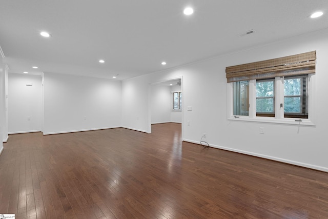 unfurnished room with baseboards, visible vents, dark wood finished floors, and recessed lighting