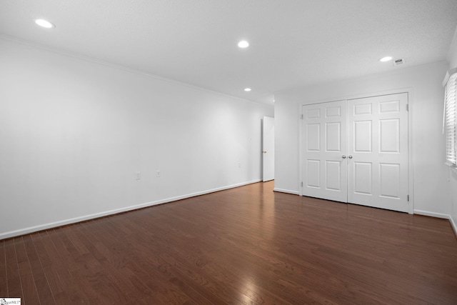 unfurnished bedroom featuring a closet, baseboards, dark wood-style flooring, and recessed lighting