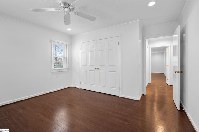 unfurnished bedroom featuring dark wood-style floors, a closet, ornamental molding, and baseboards