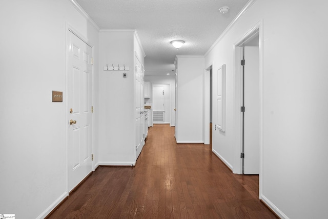 corridor featuring dark wood-style floors, crown molding, a textured ceiling, and baseboards