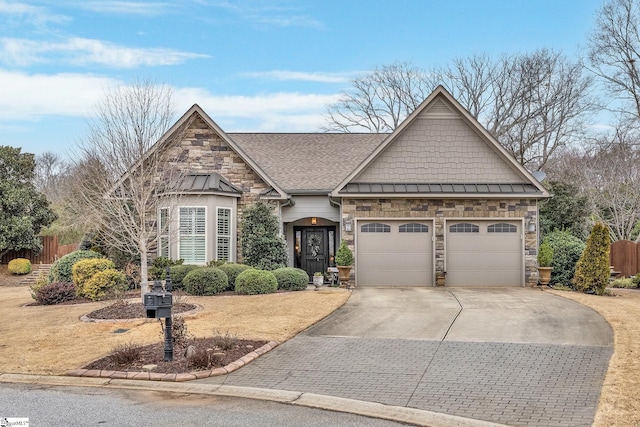 view of front facade with driveway, a garage, stone siding, metal roof, and a standing seam roof