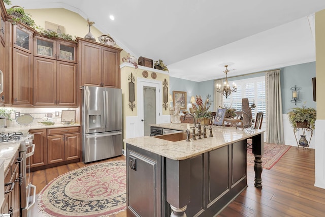 kitchen featuring appliances with stainless steel finishes, lofted ceiling, a sink, and wood finished floors