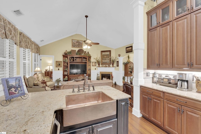 kitchen featuring a sink, visible vents, open floor plan, light stone countertops, and ornate columns