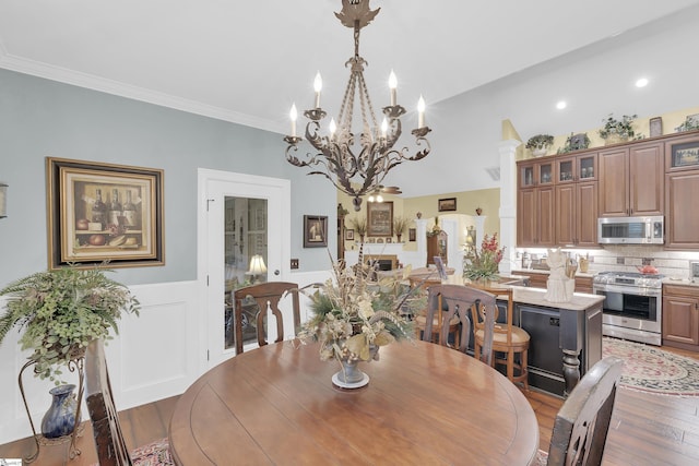 dining room featuring a wainscoted wall, crown molding, a fireplace, and wood finished floors