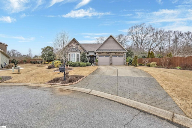 view of front of home featuring a garage, fence, driveway, stone siding, and a front yard