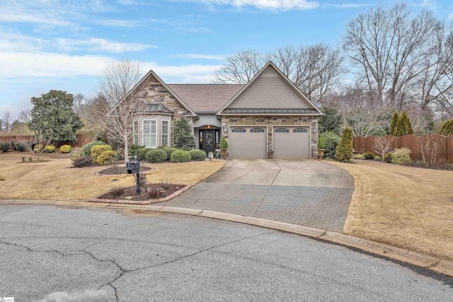 craftsman-style home featuring a front yard, fence, a garage, stone siding, and driveway