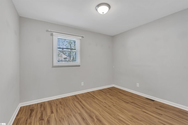 empty room featuring baseboards, visible vents, and wood finished floors