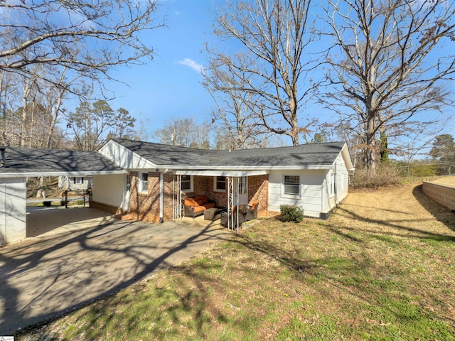 back of property featuring driveway, entry steps, a yard, a carport, and brick siding