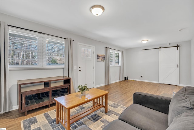 living room with light wood-style flooring, baseboards, and a barn door