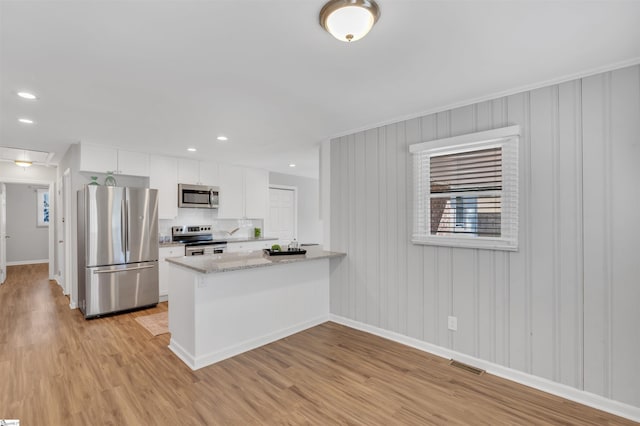 kitchen featuring stainless steel appliances, visible vents, light wood finished floors, and white cabinetry