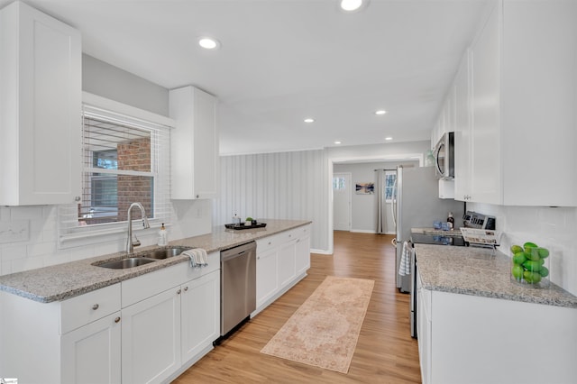 kitchen featuring a wealth of natural light, stainless steel appliances, a sink, and light wood finished floors