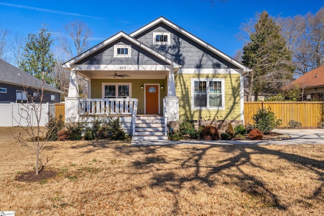 view of front of house with a front yard, covered porch, ceiling fan, and fence