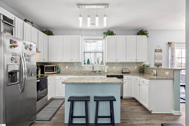 kitchen featuring stainless steel appliances, a breakfast bar, a sink, and a peninsula