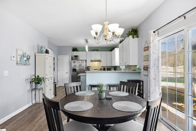 dining room featuring wood finished floors, baseboards, and an inviting chandelier