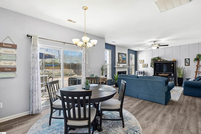 dining room with a fireplace, wood finished floors, visible vents, and baseboards