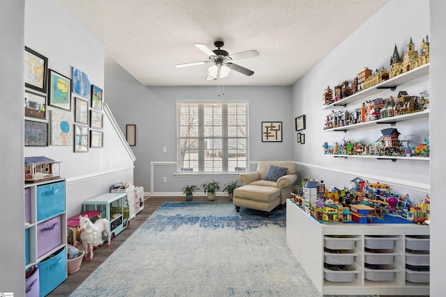 rec room featuring a textured ceiling, ceiling fan, wood finished floors, and baseboards