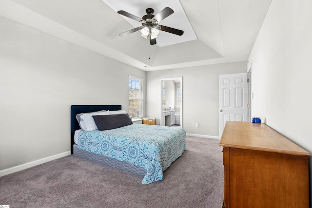 bedroom with ensuite bathroom, carpet flooring, a ceiling fan, baseboards, and a raised ceiling