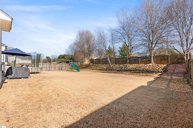 exterior space with a trampoline, a playground, and a fenced backyard