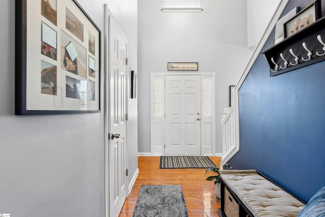 foyer with a towering ceiling, light wood-style floors, stairway, and baseboards