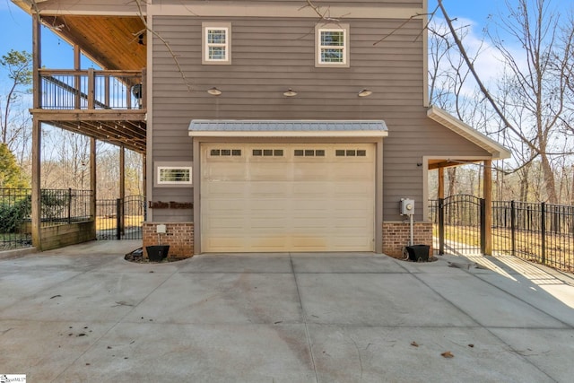 garage with driveway, a gate, and fence