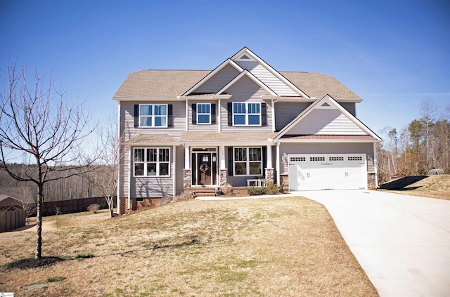 craftsman house featuring an attached garage, a shingled roof, a front lawn, and concrete driveway