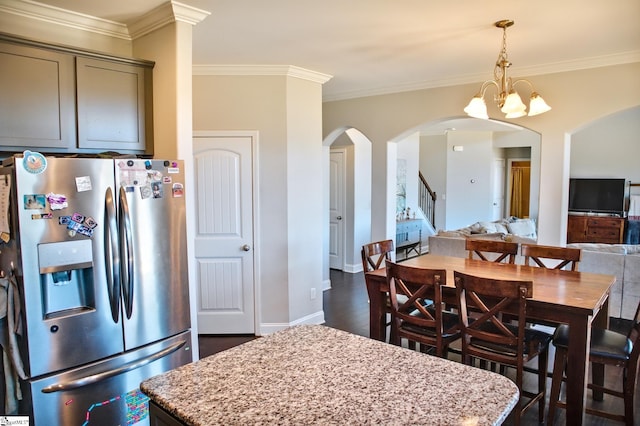 kitchen with stainless steel fridge, a kitchen island, arched walkways, and light stone counters