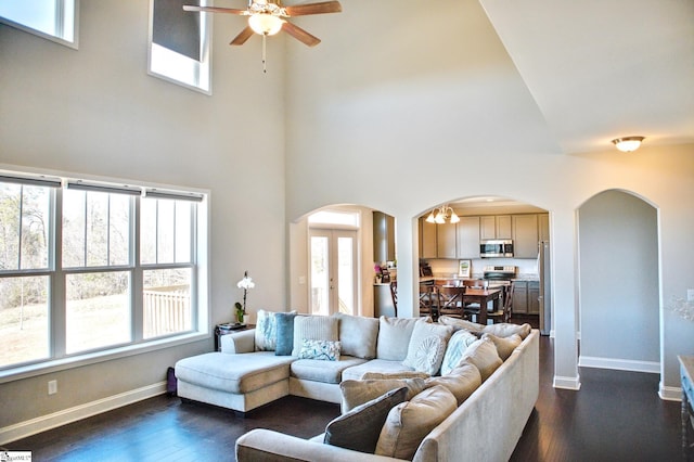 living room with baseboards, arched walkways, dark wood finished floors, ceiling fan, and french doors