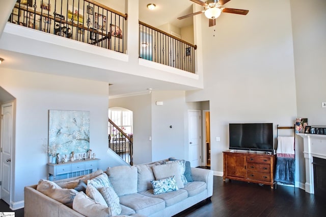 living area featuring a ceiling fan, ornamental molding, wood finished floors, baseboards, and stairs