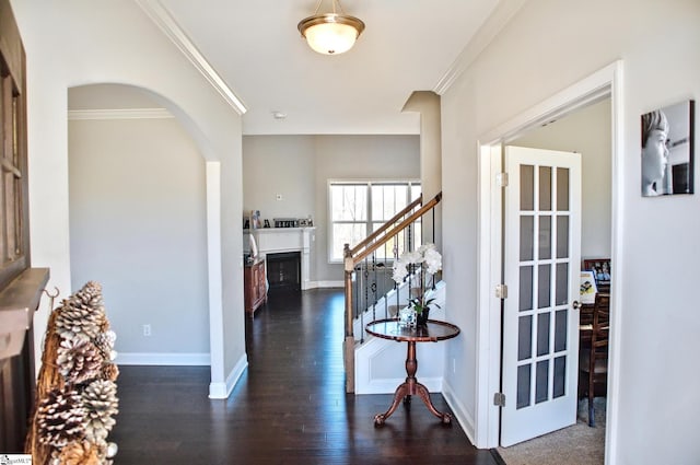 foyer featuring crown molding, a fireplace, stairway, dark wood-type flooring, and baseboards