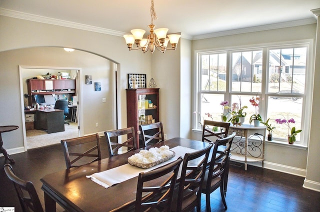 dining space featuring baseboards, arched walkways, wood finished floors, crown molding, and a notable chandelier