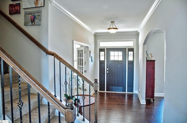 foyer entrance with arched walkways, wood finished floors, baseboards, stairs, and crown molding