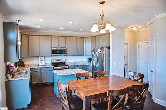 kitchen featuring dark wood-style flooring, pendant lighting, crown molding, appliances with stainless steel finishes, and a sink